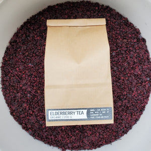 brown bag with label "Elderberry Tea" with purple dried elderberries in background